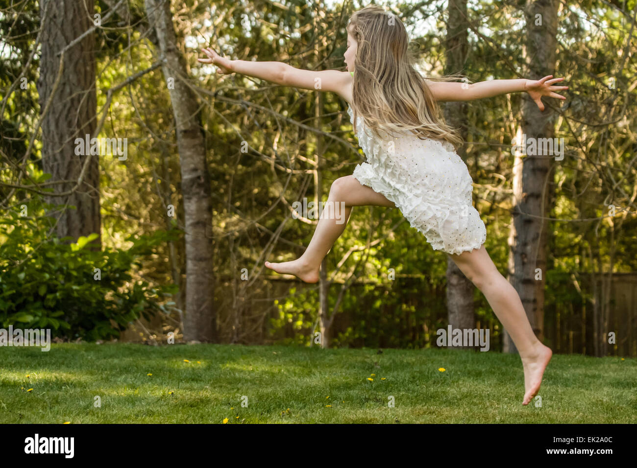 Seven year old girl leaping in the air in her backyard in Issaquah, Washington, USA Stock Photo