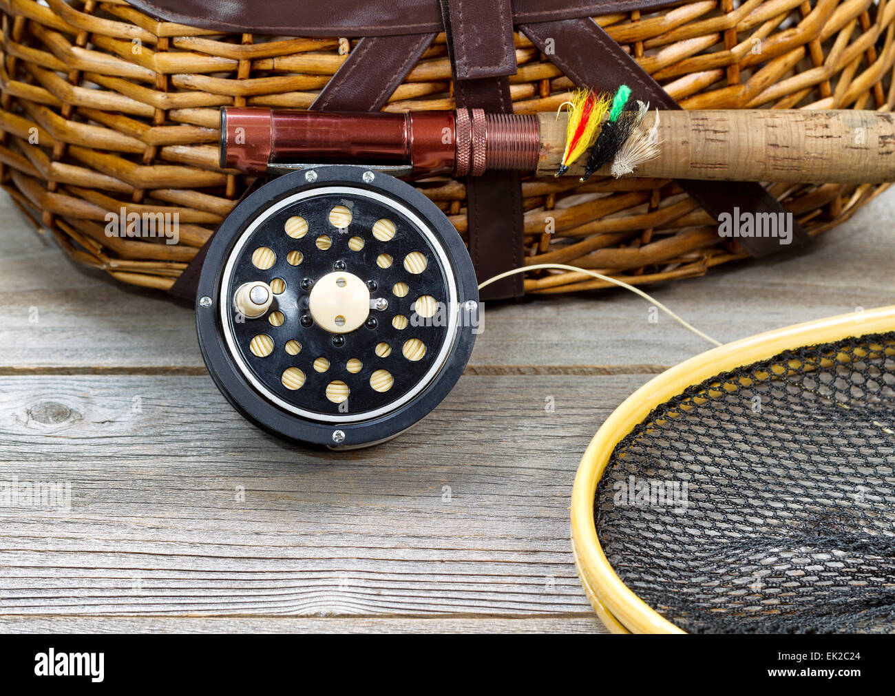 antique fly fishing reel, rod, landing net, creel and artificial flies on rustic wood. Layout in horizontal format. Stock Photo