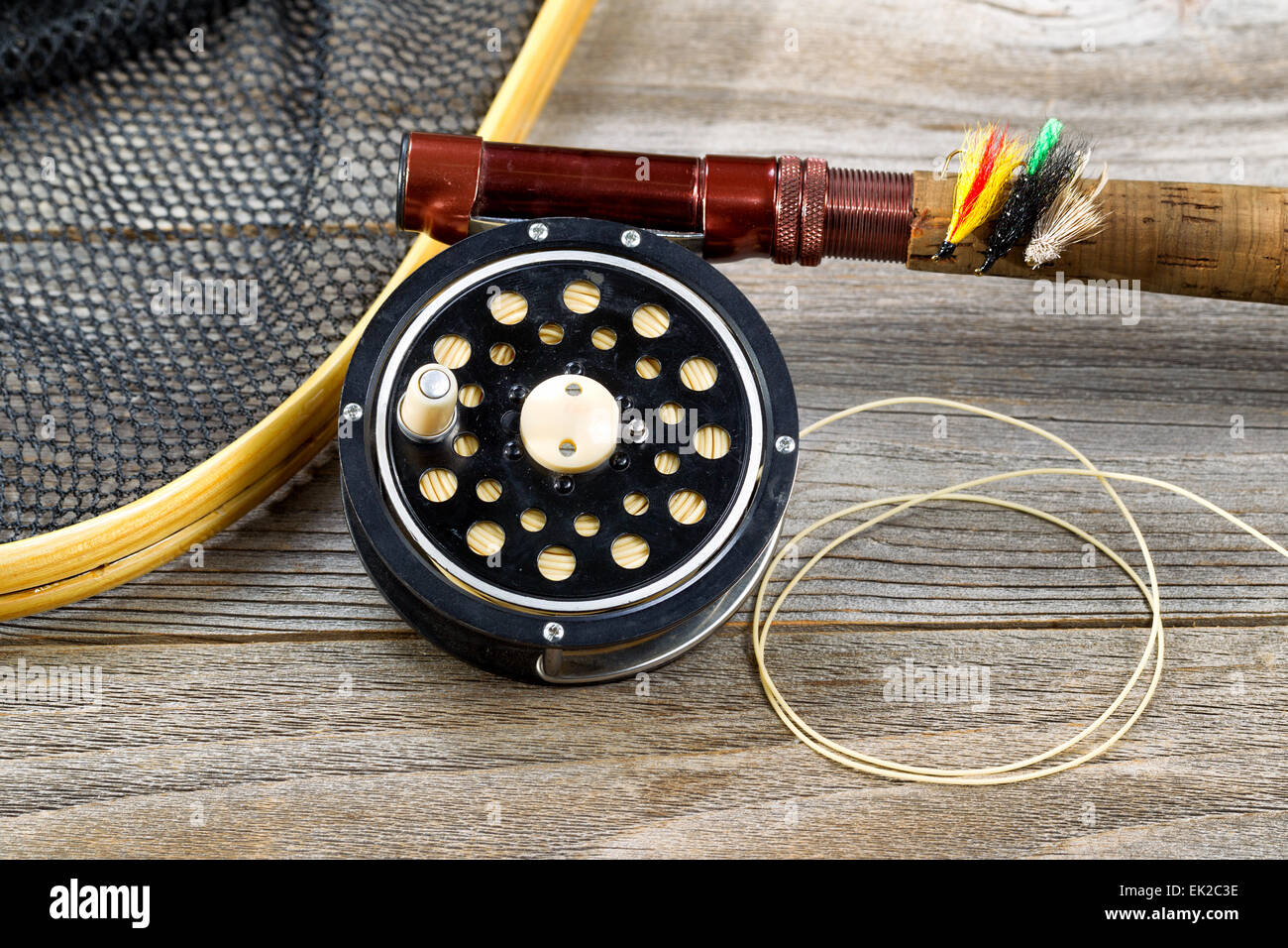 Close up of an antique fly fishing reel, rod, landing net and artificial flies on rustic wood. Layout in horizontal format. Stock Photo