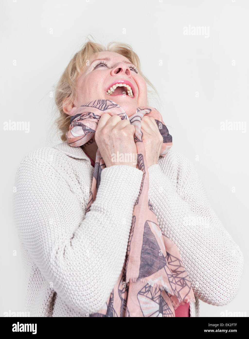 an older woman with blond hair is happy and looking upwards Stock Photo