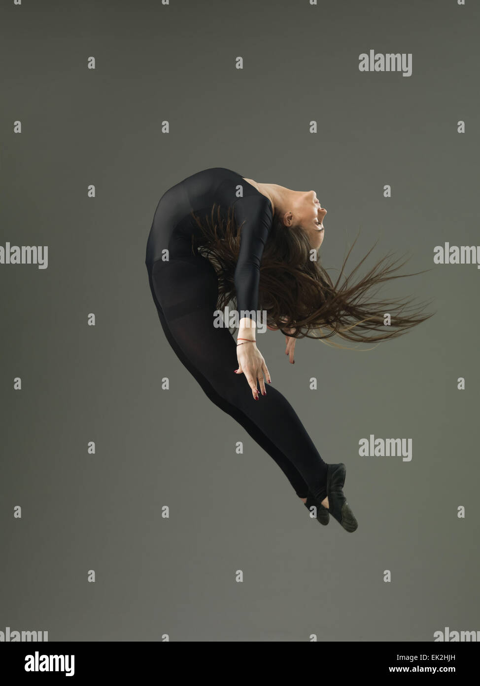dancer performing high jump and backbend against grey background Stock ...