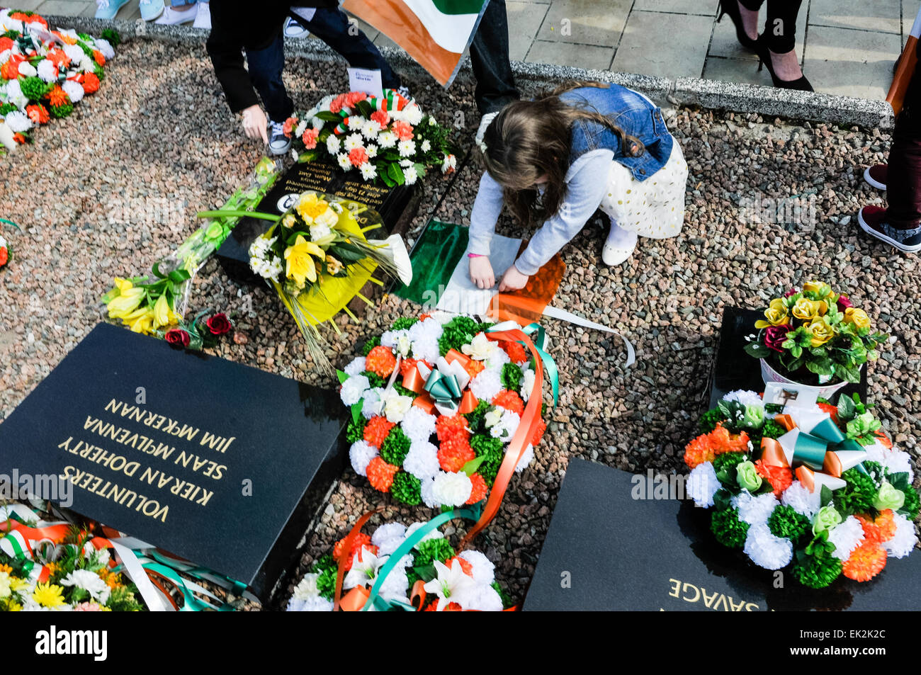 A young girl lays a wreath at the IRA Republican plot in Milltown Cemetery, Belfast Stock Photo