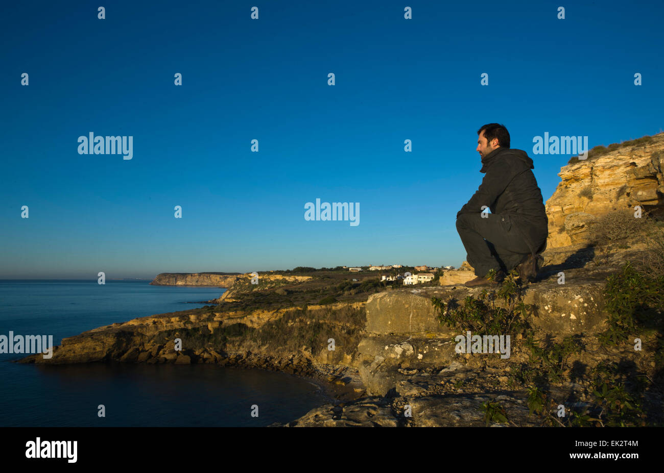 Man by himself on cliff overlooking sea Stock Photo