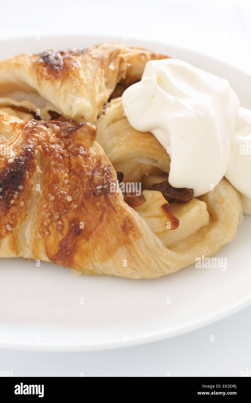 Apple strudel Danish pastry filled with apple cinnamon and sultanas served with whipped cream Stock Photo
