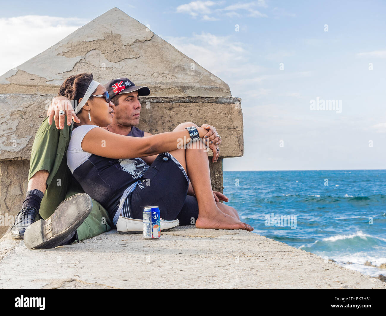 Two middle-age Cuban lovers on the Malecón wall by Havana harbor with the man pouting. Stock Photo