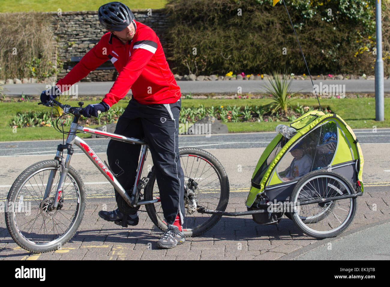 Man in helmet towing bike trailer with young child also wearing cycle  helmet inside Stock Photo - Alamy