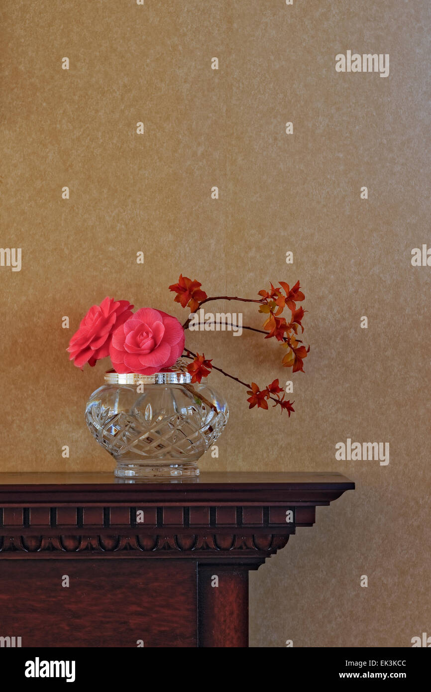 Flower arrangement, including camellia flowers, in a crystal vase on carved  wooden mantelpiece against plain wallpaper; portrait​ orientation Stock  Photo - Alamy