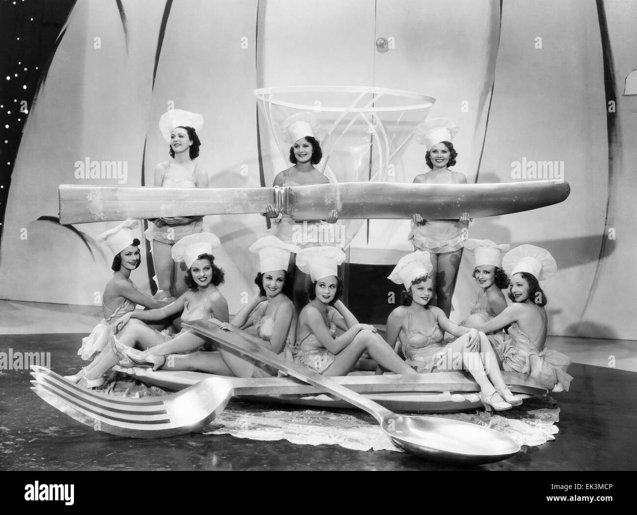 Chorus Girls with Large Spoon, Fork & Knife, on-set of the Film 'Merry-Go-Round of 1938', 1937 Stock Photo