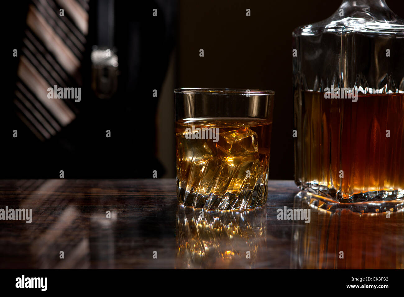 A glass of whiskey on the rocks next to a bottle at home. Stock Photo