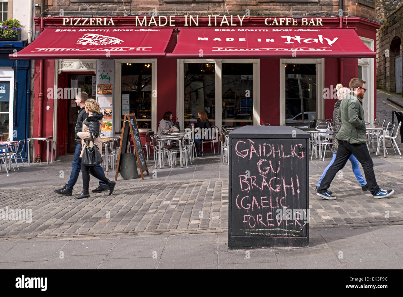 Gaelic graffiti with translation chalked on a utility box outside an Italian restaurant in the Grassmarket area of Edinburgh. Stock Photo