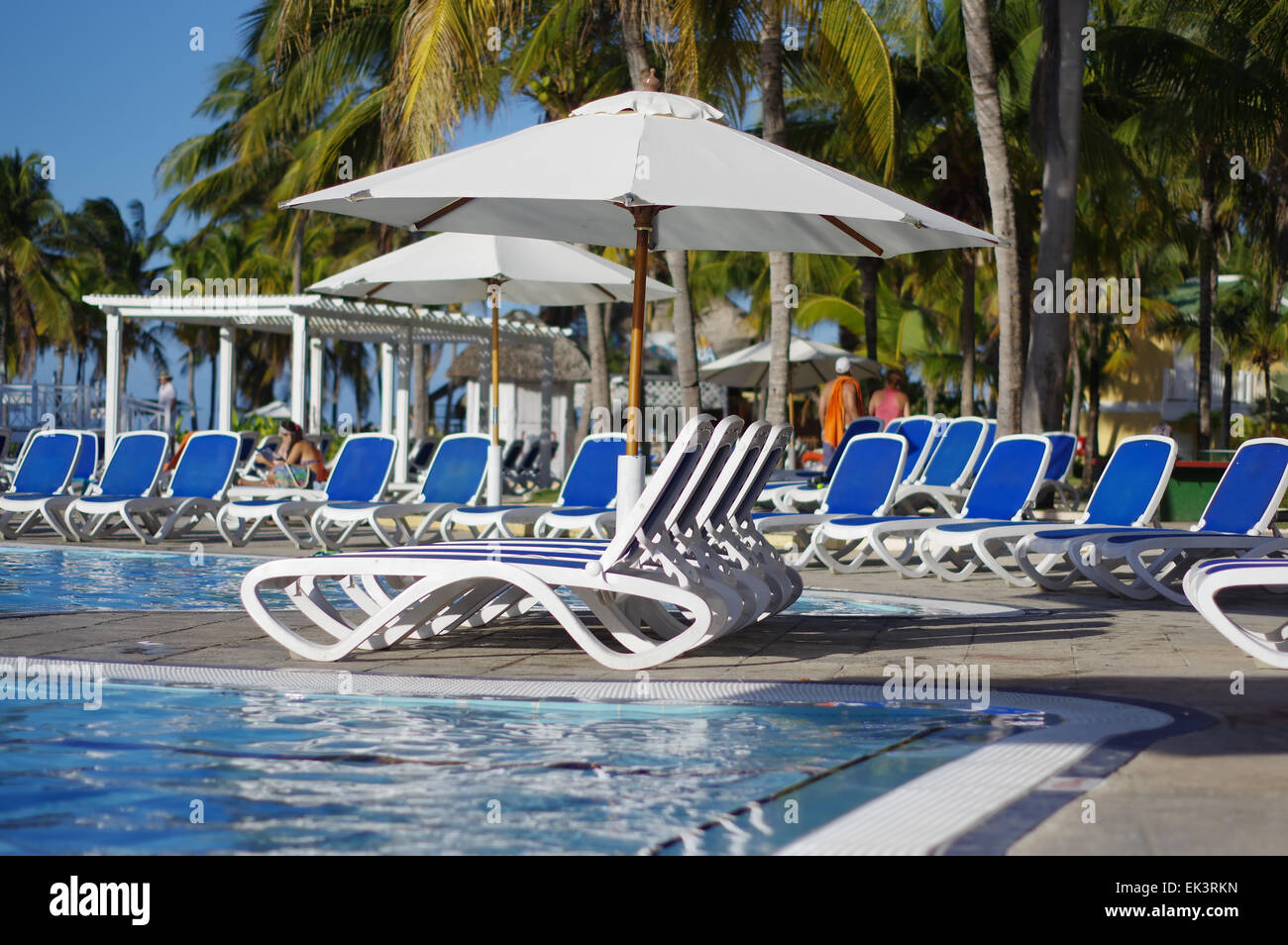 Lounge chairs around a swimming pool at a tropical resort Stock Photo