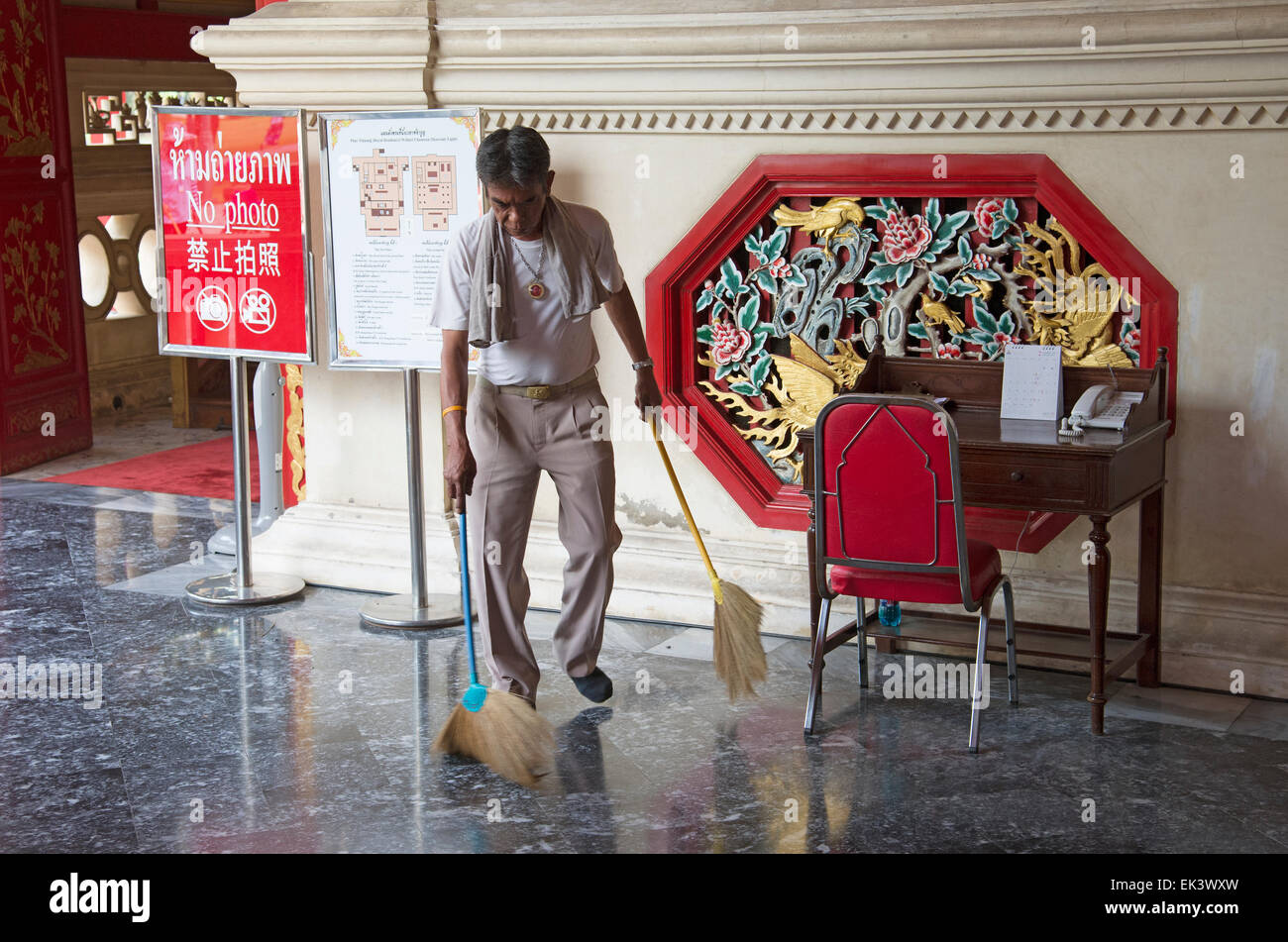 Man using two brushes to sweep a floor at Phar Thinang a royal residence at Ayutthaya Thailand Stock Photo