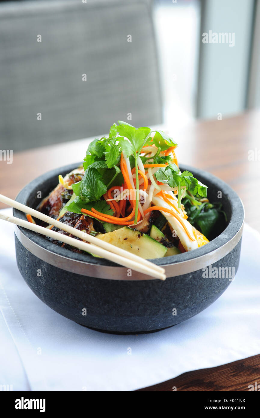 USA Food Dining Asian style chicken rice bowl in a fusion restaurant  served with cilantro pickled vegetables and chopsticks Stock Photo