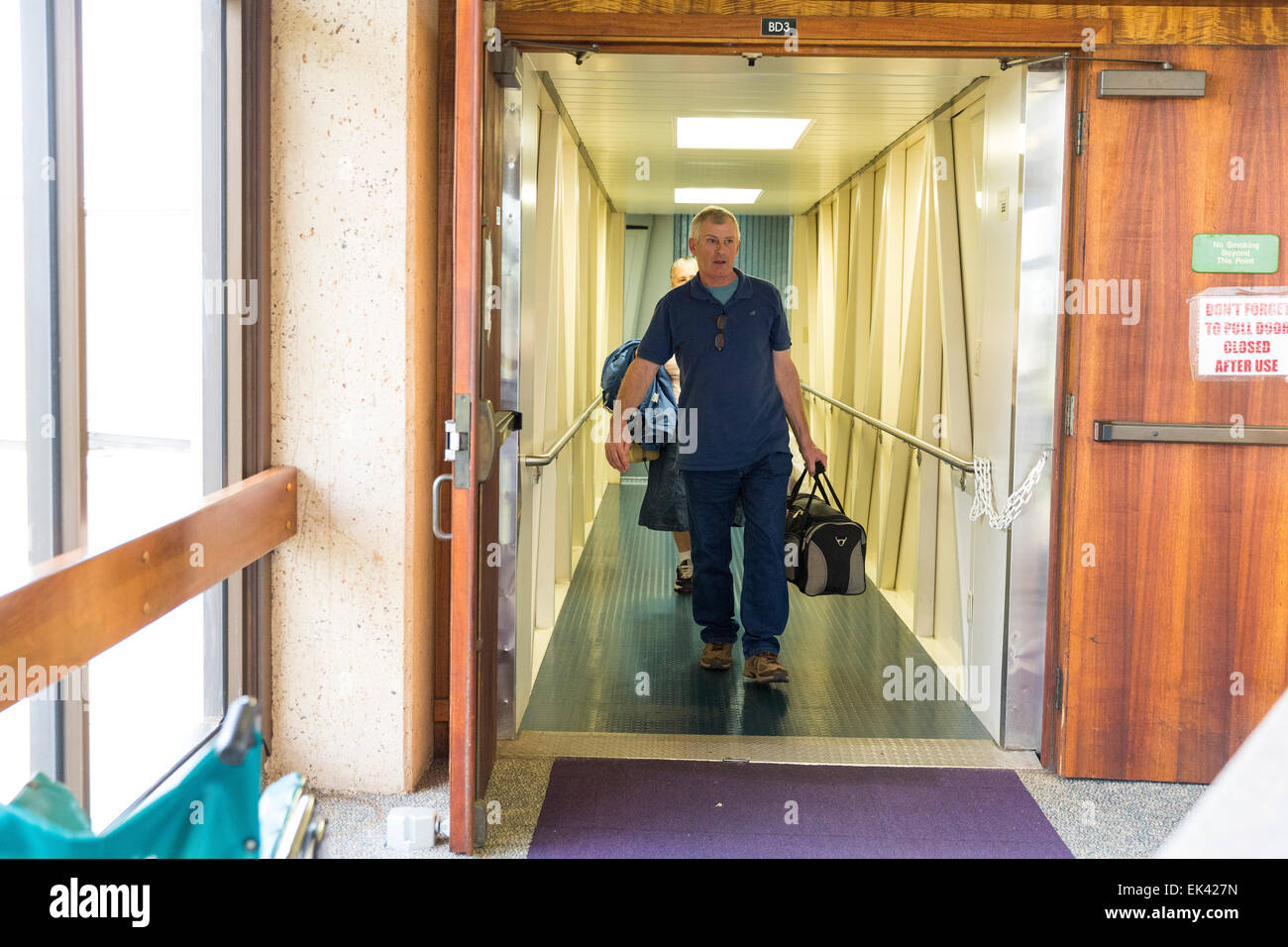 Man carrying a carry on baggage walking out of the just arrived