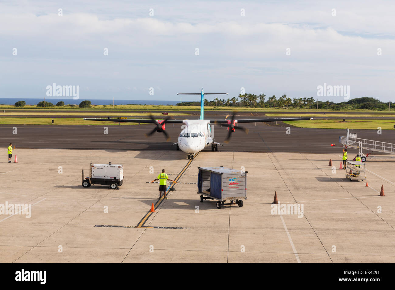 Airplane on a tarmac at the Kauai Airport, Hawaii with workers directing the traffic Stock Photo