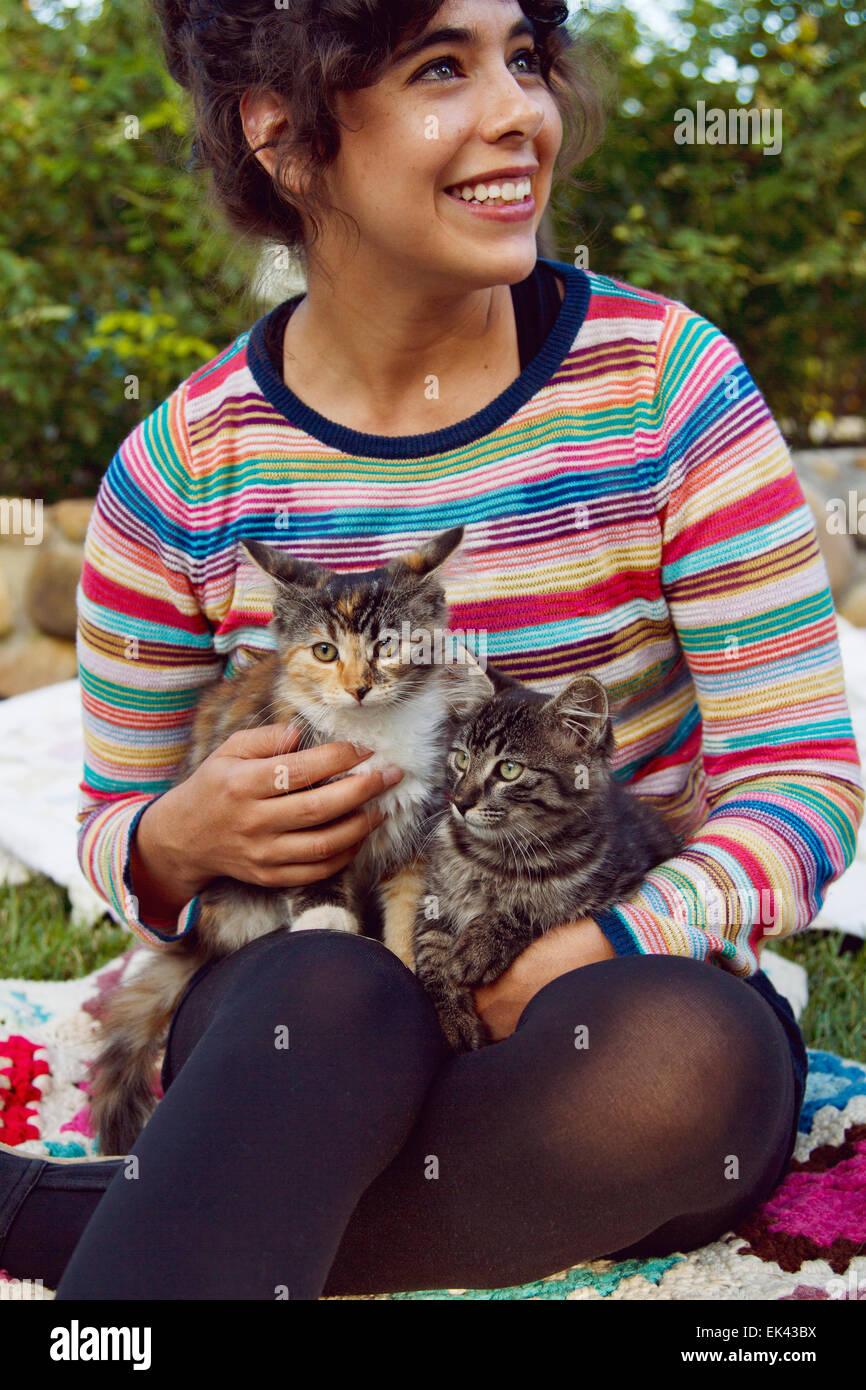 Woman cuddling kitten's while sitting on a blanket outside Stock Photo
