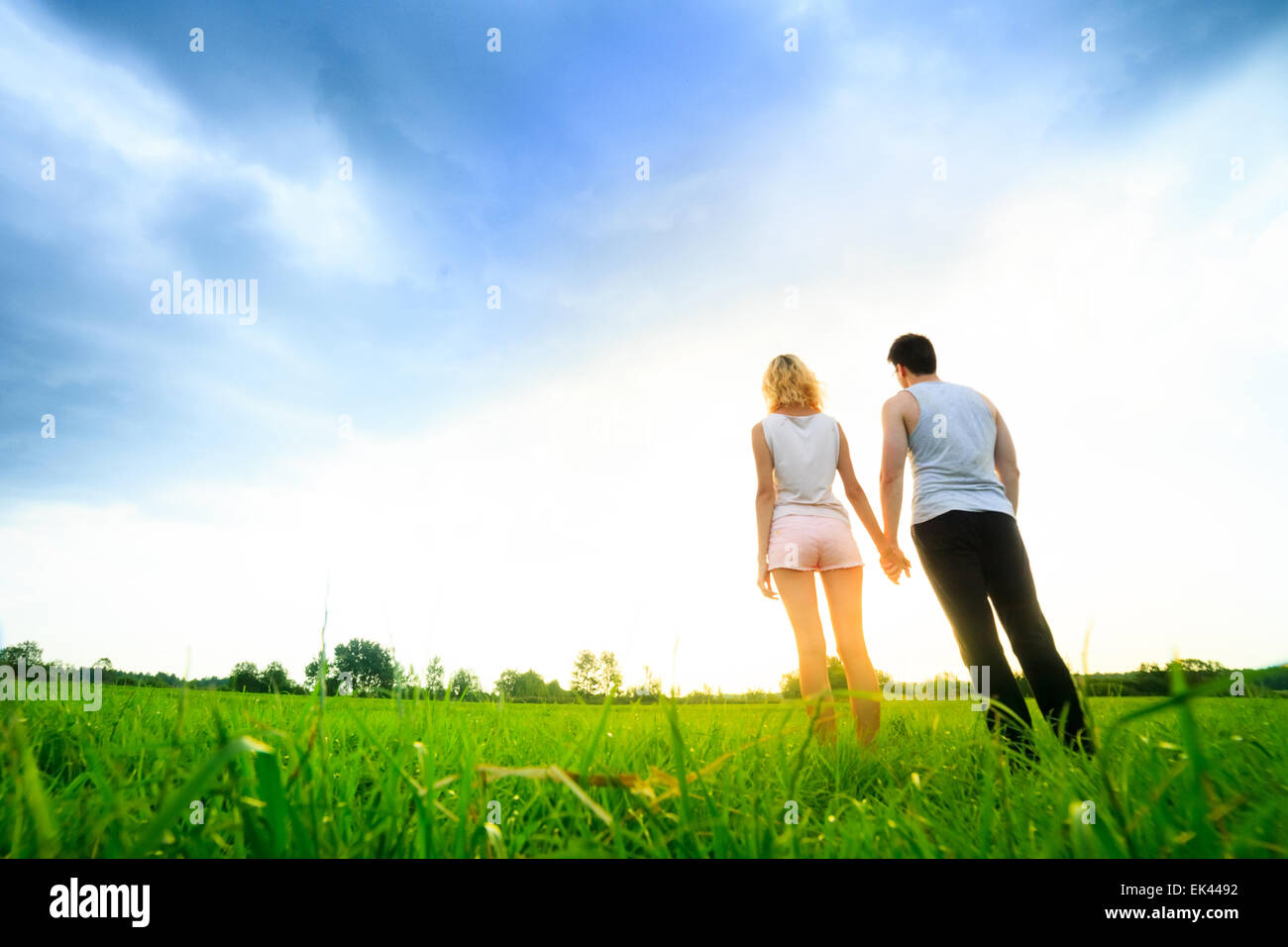 couple walking through the field and holding hands Stock Photo - Alamy