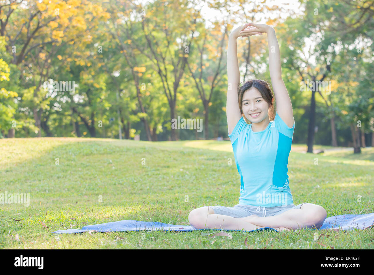 fitness, sport, training and lifestyle concept - Asian woman stretching outdoors Stock Photo