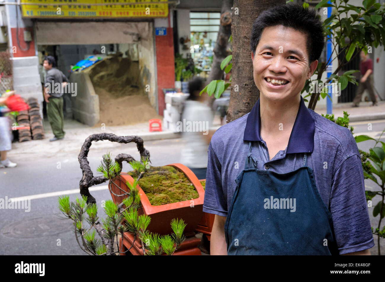 Man in China selling miniature penzai (otherwise known as penjing) trees, the Chinese version of bonsai. Street stall, Guangzhou, Young man; seller Stock Photo