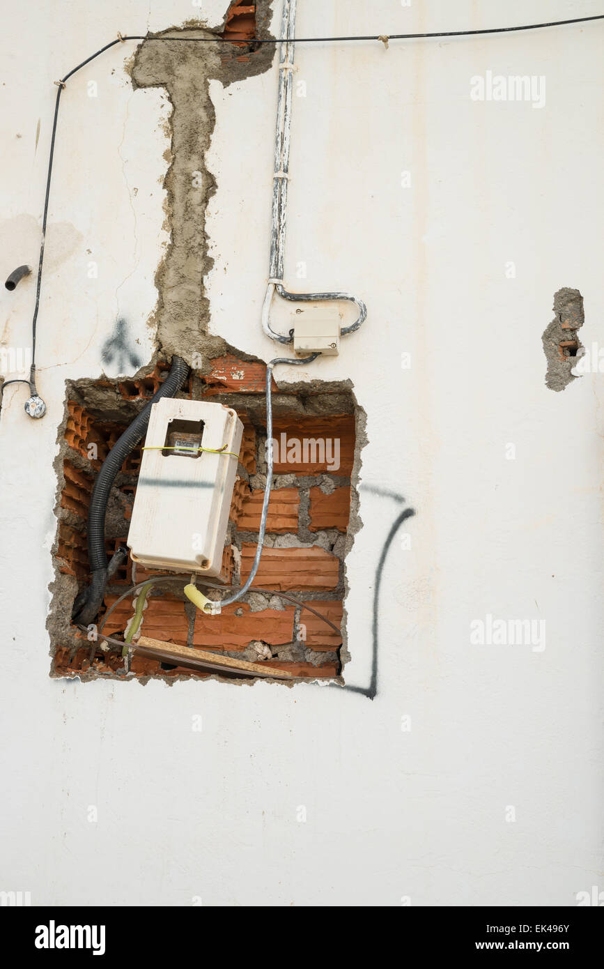 Unfinished wiring and electricity meter on a wall Stock Photo