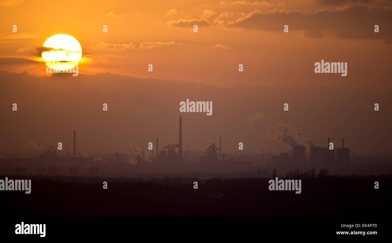 The sun sets behind the steel mill Duisburg-Bruckhausen of German manufacturer ThysssenKrupp Steel Europe in Duisburg, Germany, 10 March 2015. The picture was taken from an elevated location in Essen-Kettwig. Photo: Volker Hartmann/dpa Stock Photo