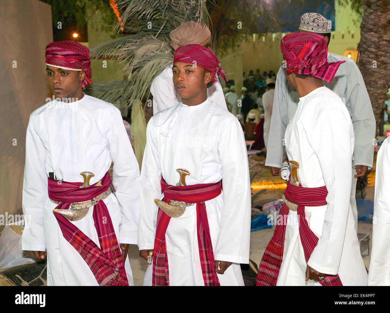 Three young Omani men in traditional dress, with khanjars (Arabian daggers), at a cultural 