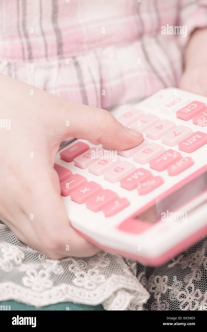 Little girl holding calculator in her hand. She is learning mathematics. Stock Photo