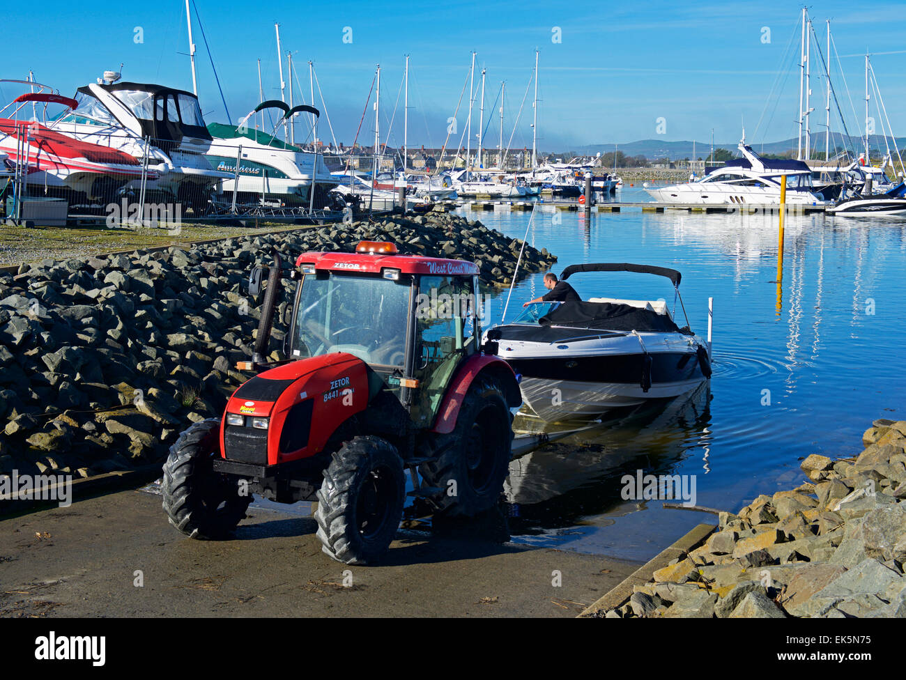 Tractor towing boat out of the water, the marina, Pwllheli, Gwynedd, North Wales UK Stock Photo