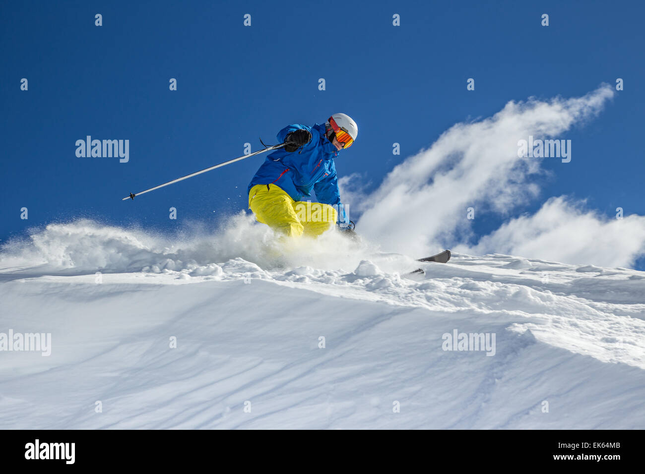 Skier skiing downhill in high mountains during sunny day. Stock Photo