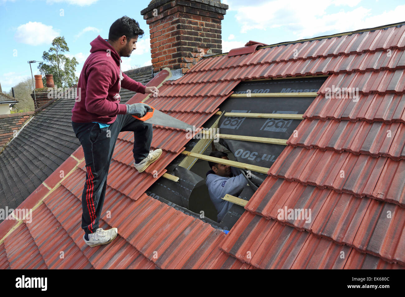 builders preparing to install a roof window on a pitched tiled roof in South London Stock Photo