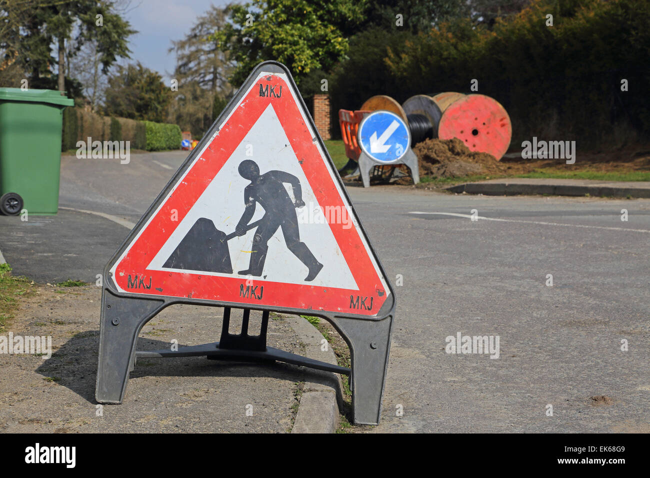 A contractors roadworks warning sign in a rural residential street. Keep left sign and reels of cable in the background Stock Photo