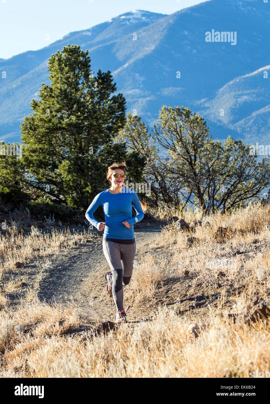 Beautiful young long haired woman running on mountain trails near
