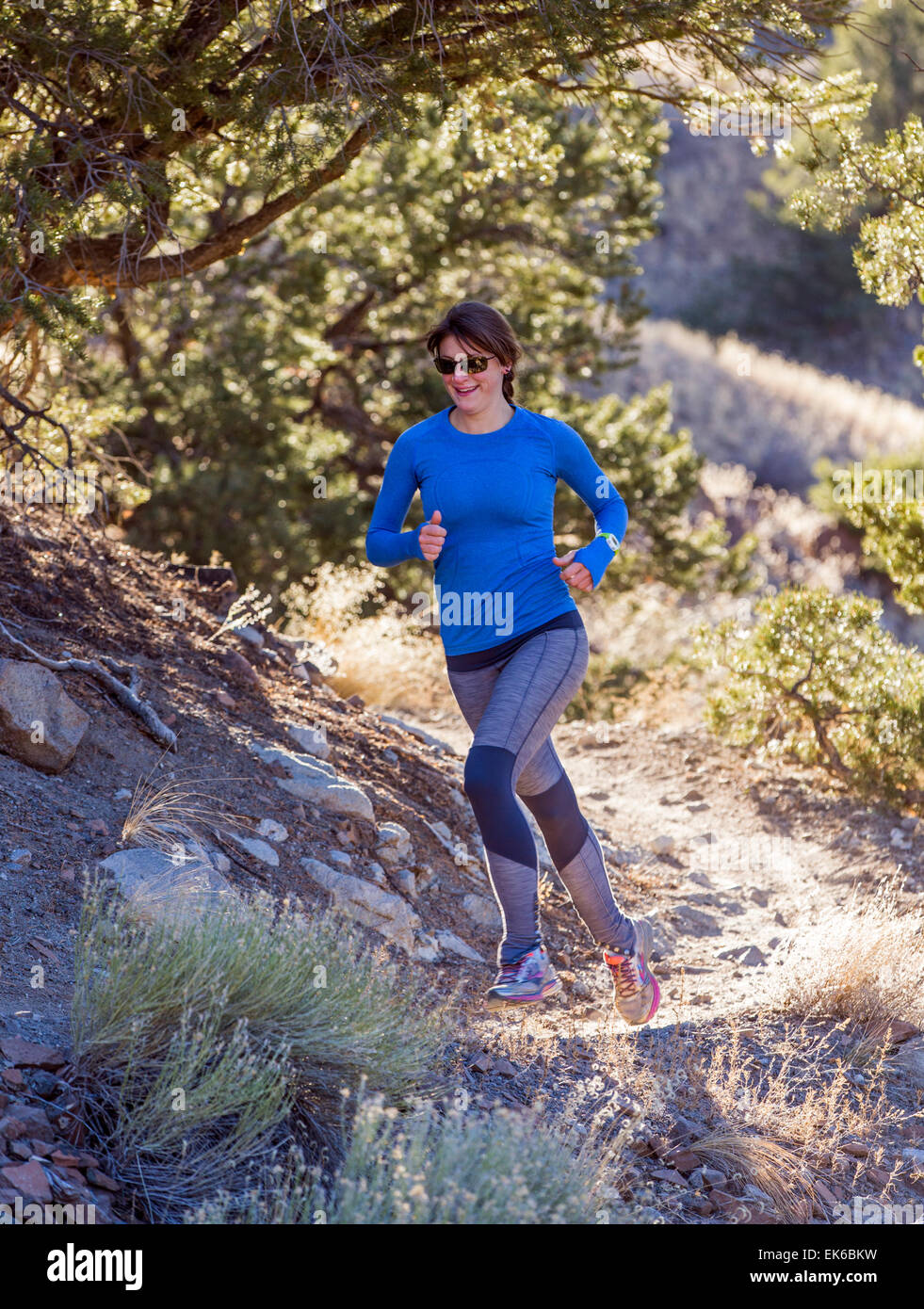 Beautiful young long haired woman running on mountain trails near
