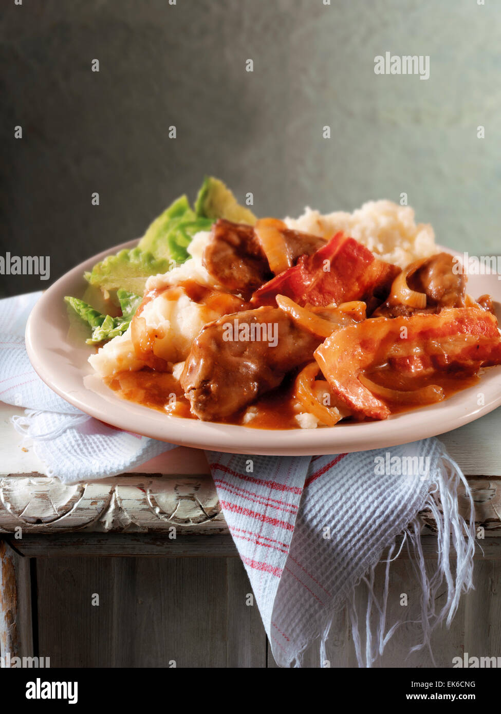 Traditional British cooked recipe of liver & bacon casserole with mashed potato served on a plate in a rustic table setting Stock Photo