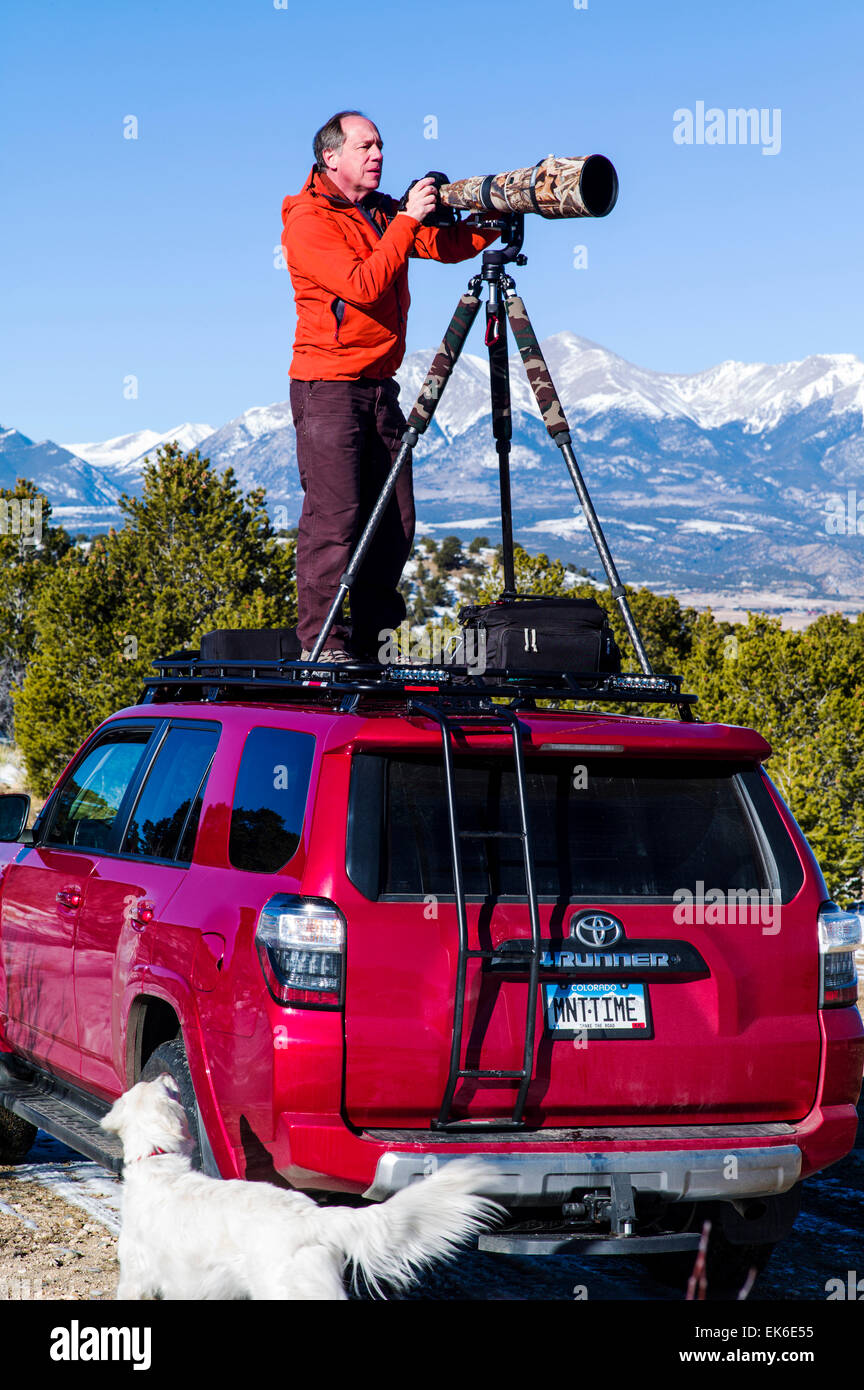 Professional photographer H. Mark Weidman shooting with a long telephoto lens from atop a Toyota 4Runner truck Stock Photo