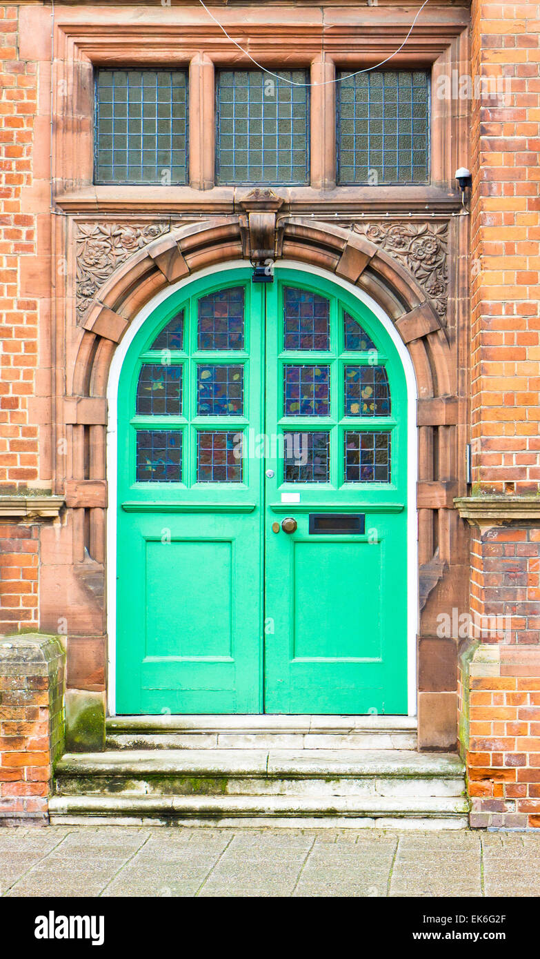 A green double arched door in a red brick building in the UK Stock Photo