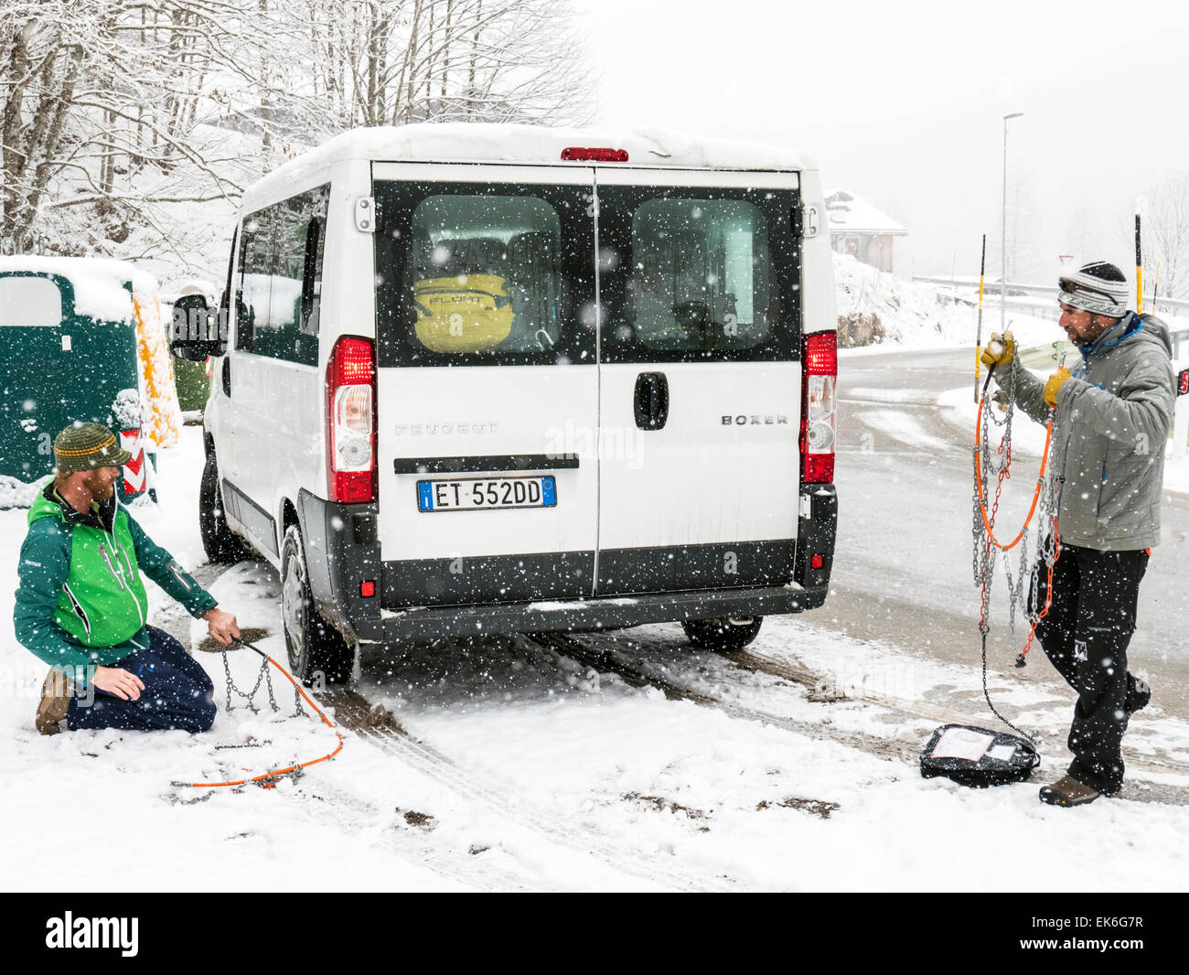 American skiers putting chains on a rental van, Dolomite Mountains, northern Italy Stock Photo