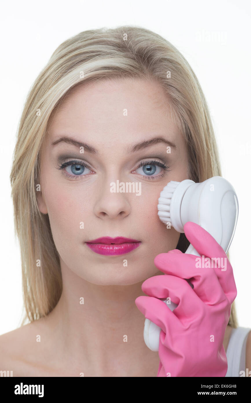 blonde woman using a face cleansing brush Stock Photo