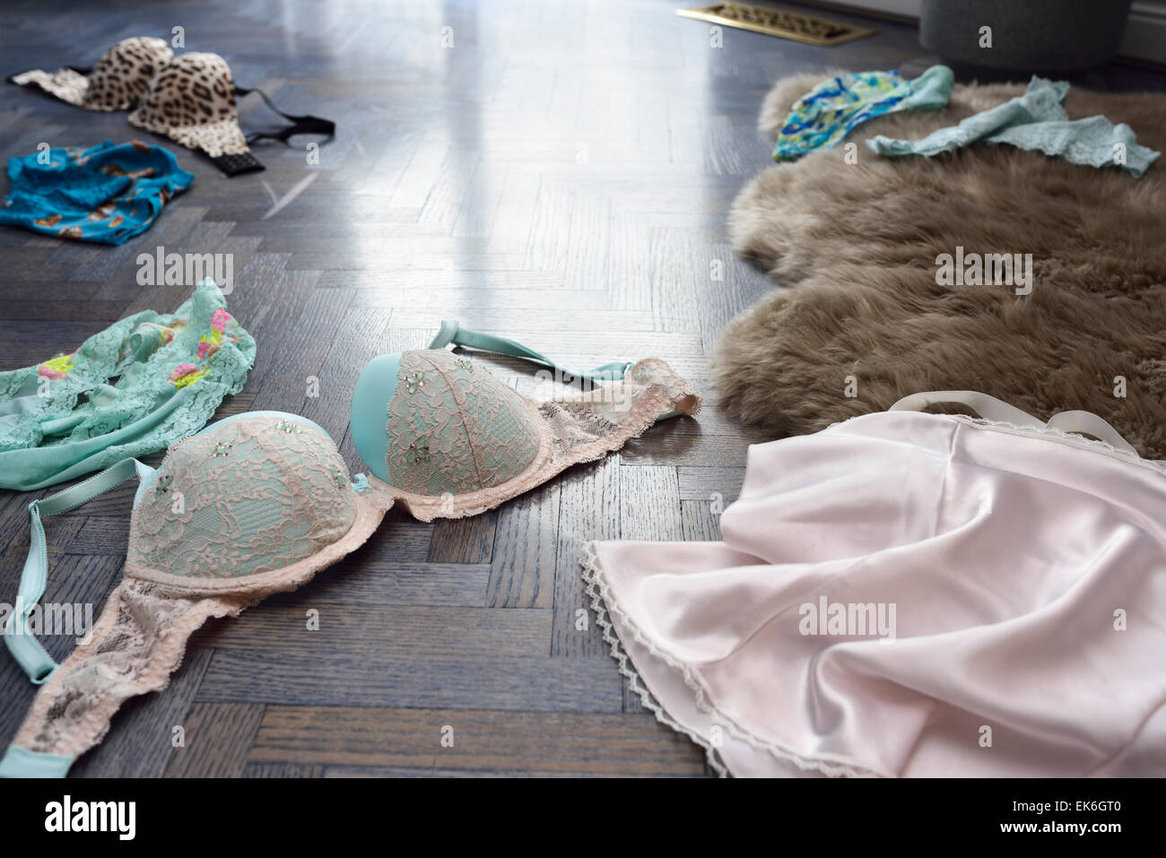 Bras and womans undergarment lingerie panties and slip strewn on a blue  stained oak floor Stock Photo - Alamy