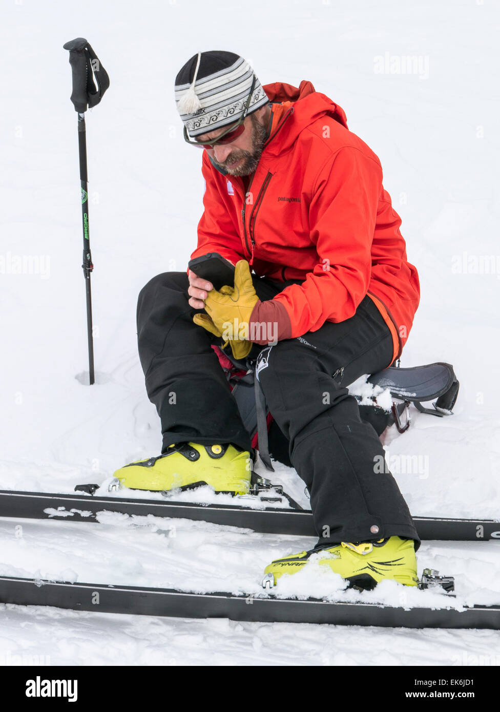 Backcountry skier checking Apple iPhone near the Rifugio Fuciade, Pale di San Martino, Dolomite Mountains, Alps, Italy Stock Photo
