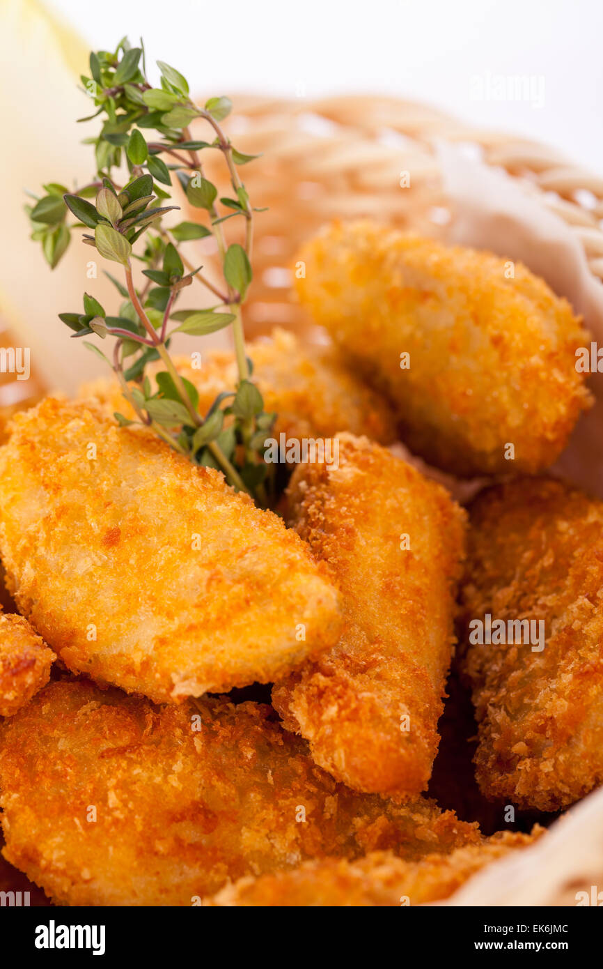 Crisp crunchy golden chicken legs and wings deep fried in bread crumbs and served with a bowl of dip in a wicker basket for a de Stock Photo
