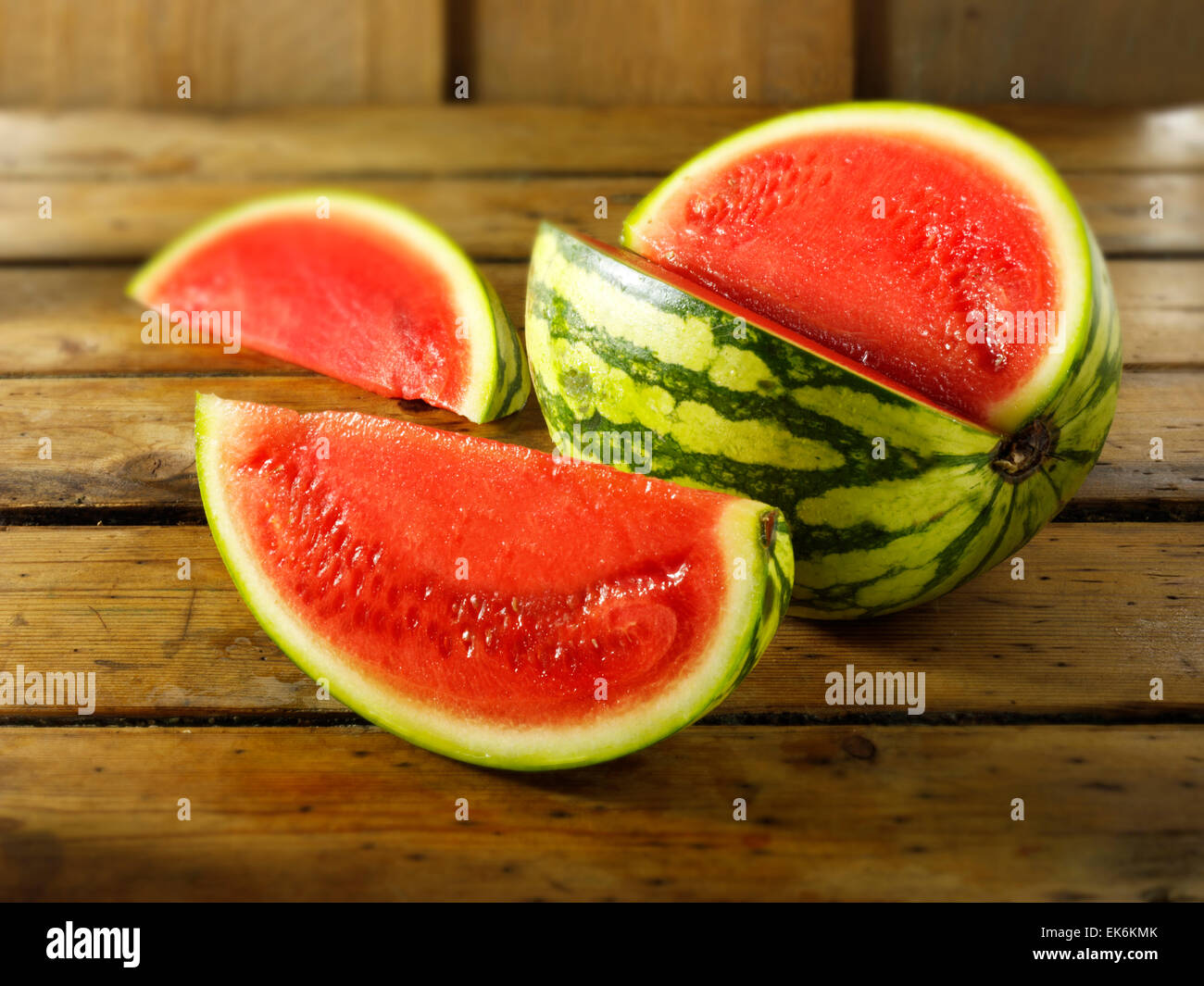 Fresh cut red watermelon, whole and sliced, on a wood background setting Stock Photo