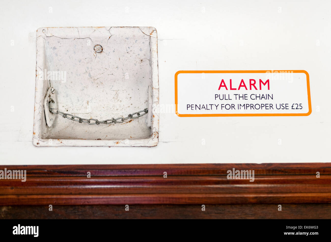 Passenger alarm chain inside an old fashioned railway carriage, and sign warning about improper use Stock Photo