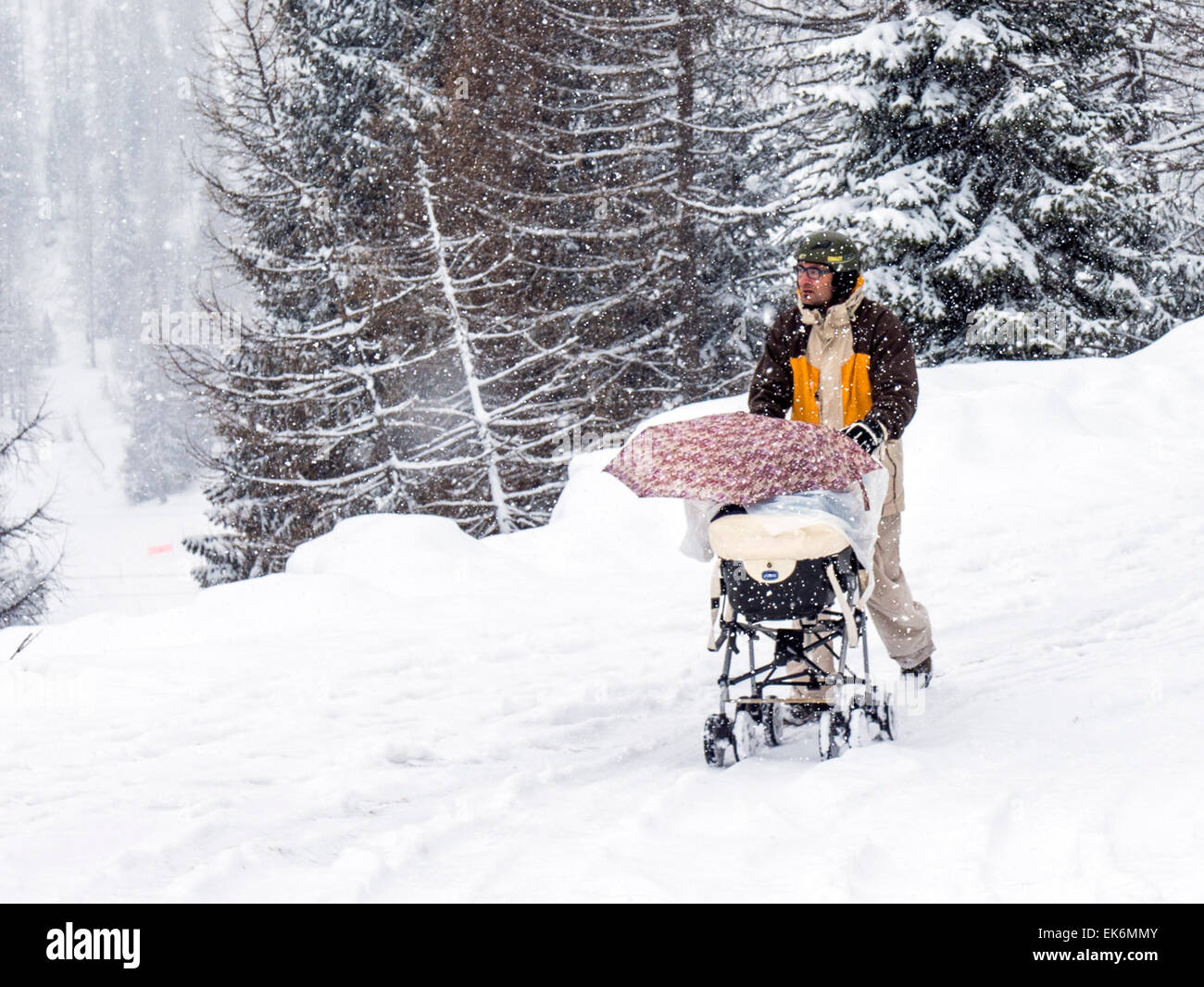 Man pushing a baby carriage in snow near the Rifugio Fuciade, Dolomite Mountains, Alps, Italy Stock Photo