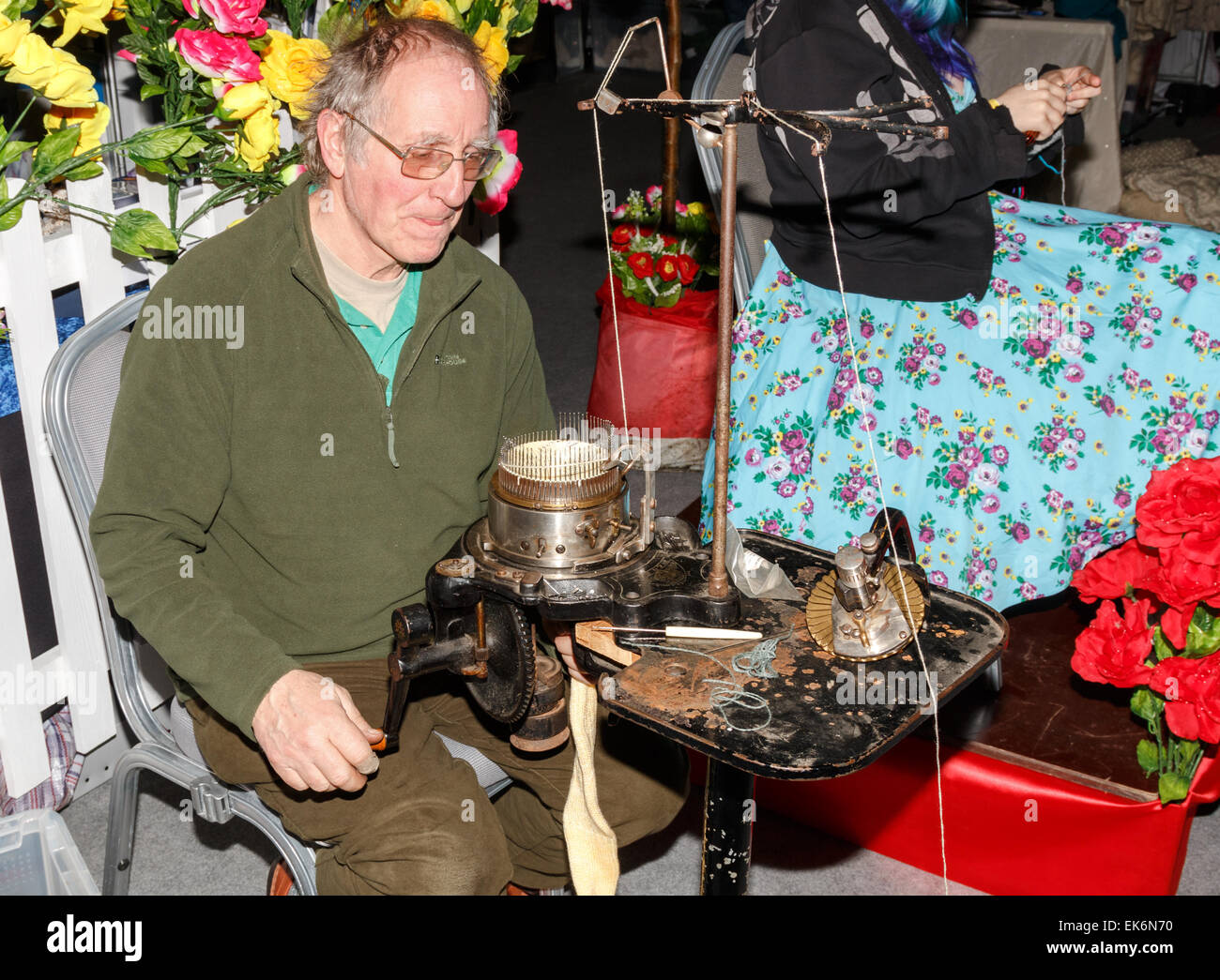 Circular sock making machine being used by a middle-aged male.  The machinery is antique. Stock Photo