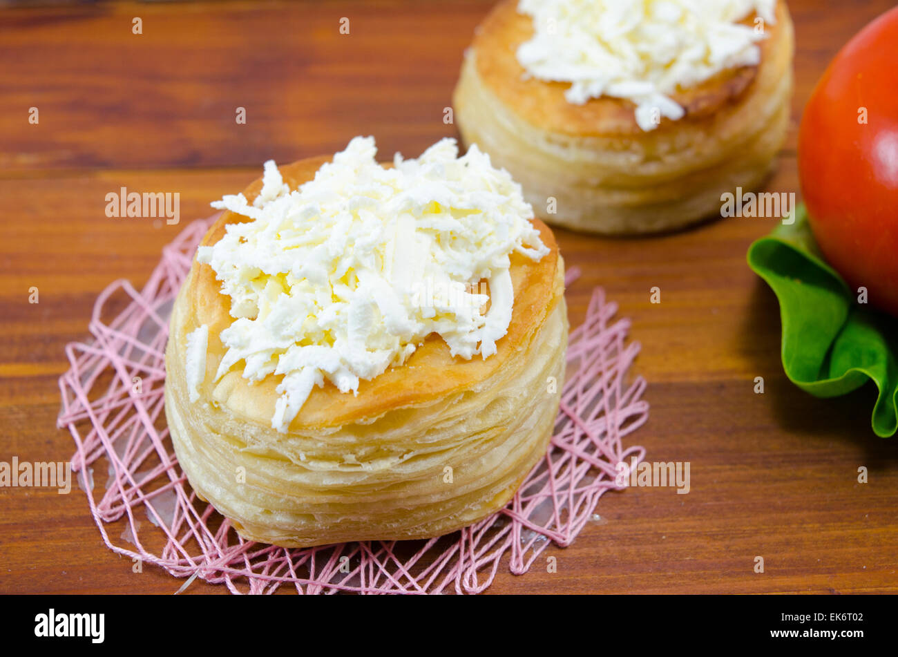 Homemade puff  pastry with cheese and tomato on a wooden table Stock Photo