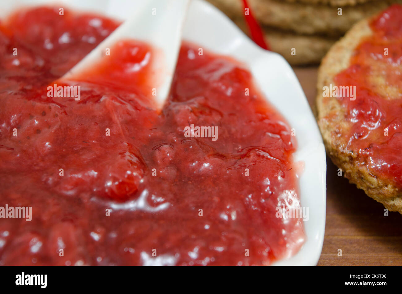 Several chocolate cookies covered with strawberry jelly on a wooden table Stock Photo
