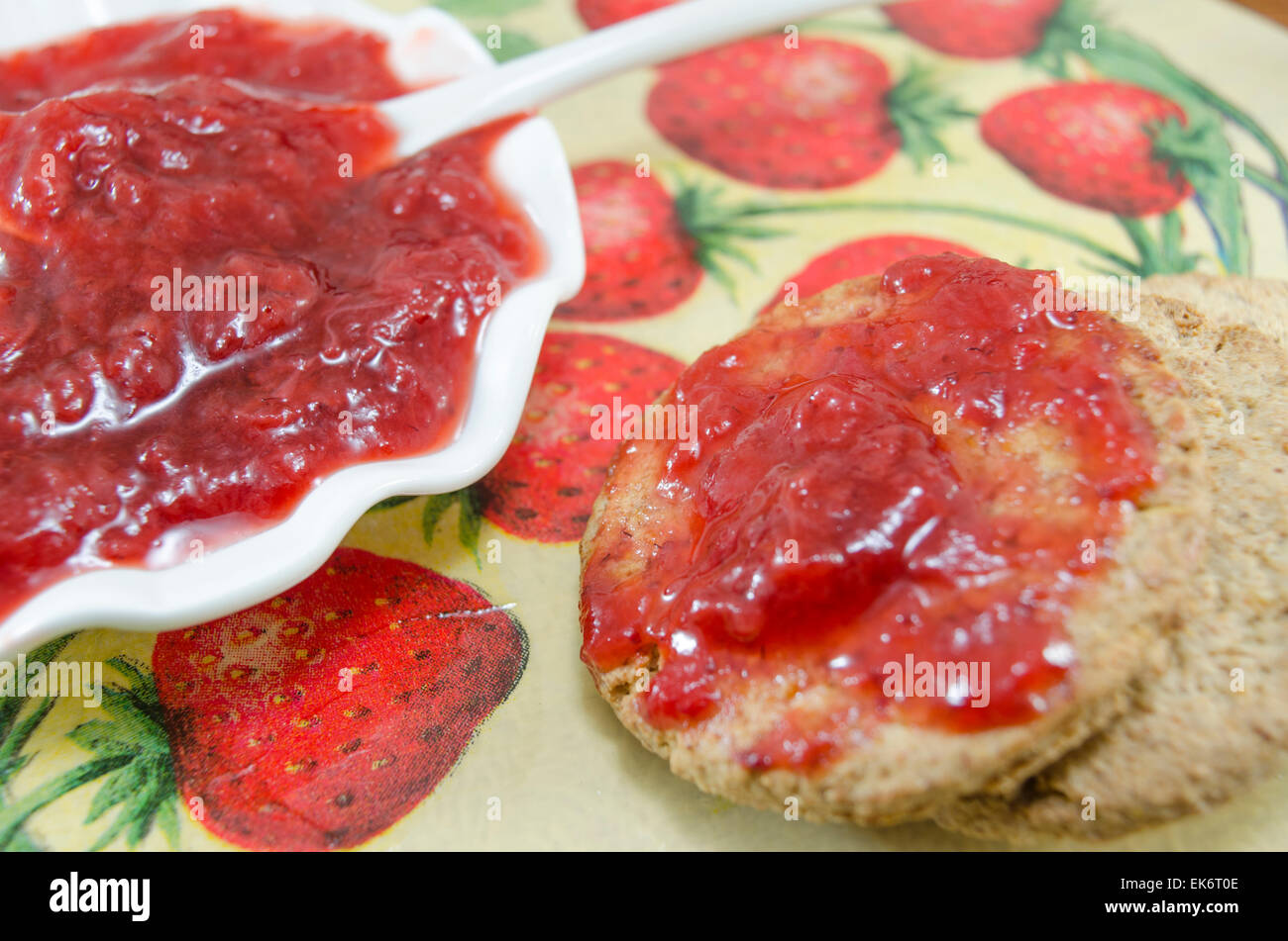 Several chocolate cookies covered with strawberry jelly on a wooden table Stock Photo