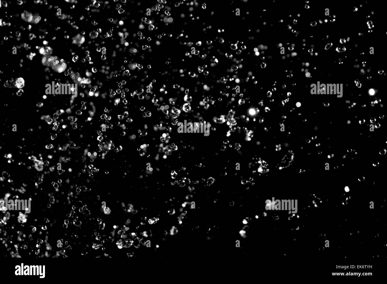 Water splash levitating. Drops of transparent liquid flying on black background. Stock Photo
