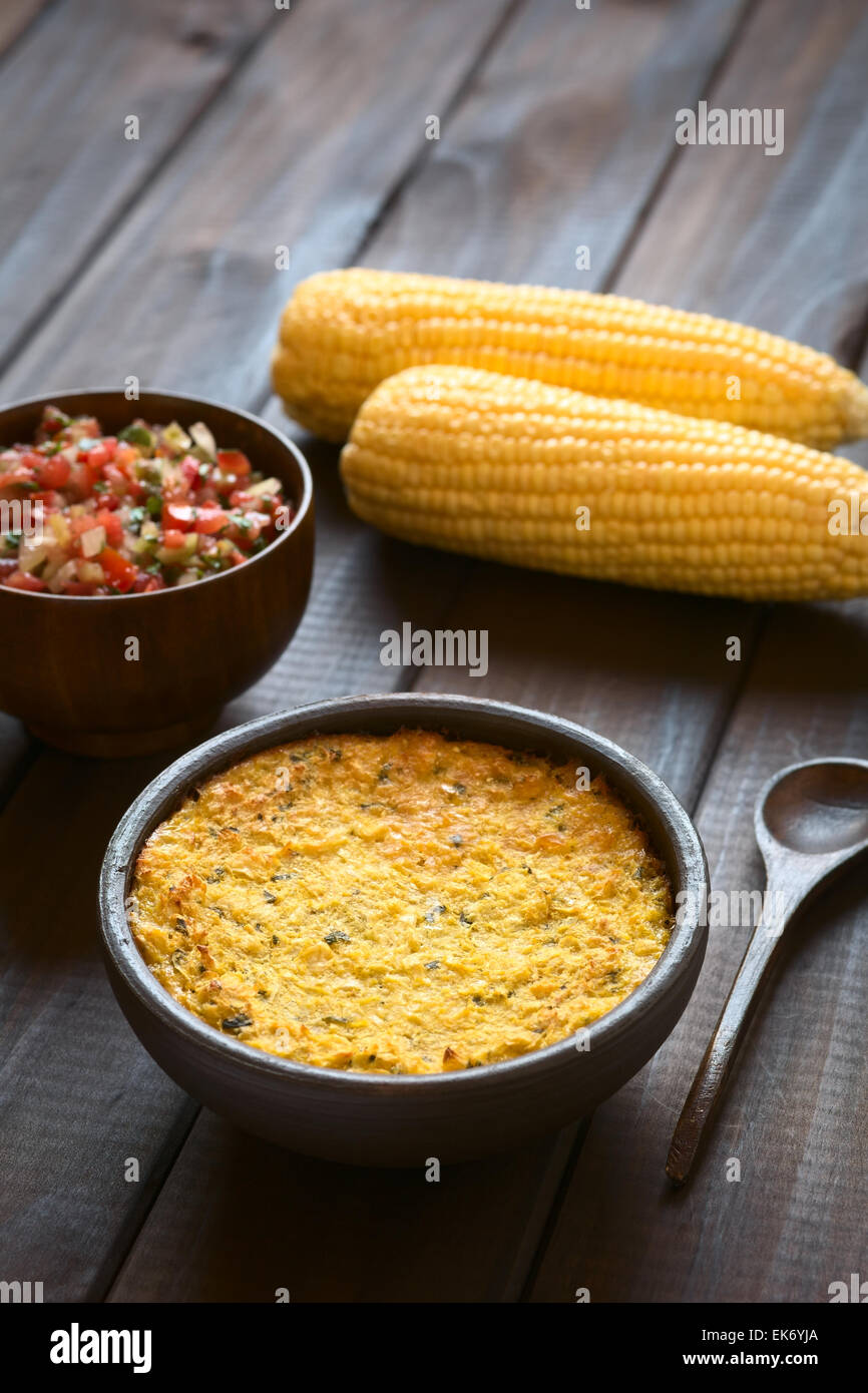 Bowl of traditional Chilean corn pie called Pastel de Choclo served with Pebre sauce and corn cobs in the back Stock Photo